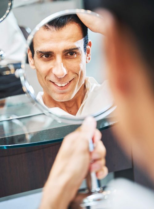 male-checking-his-appearance-in-makeup-mirror-CMY69E3-scaled.jpg